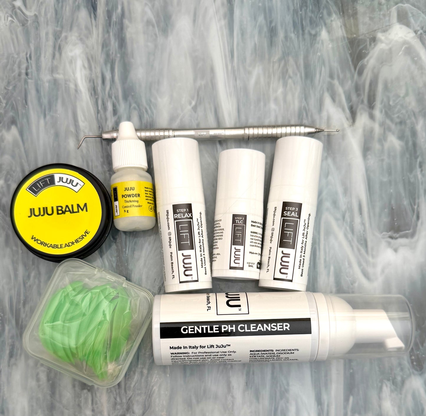 Wider flat lay of the Lift JuJu Combo Kit for keratin and cysteamine lash lifting and brow lamination with Step 1–3, Gentle pH Cleanser, JuJu Balm, JuJu Powder, ball tip isolation tool, and dual green shields on gray textured background